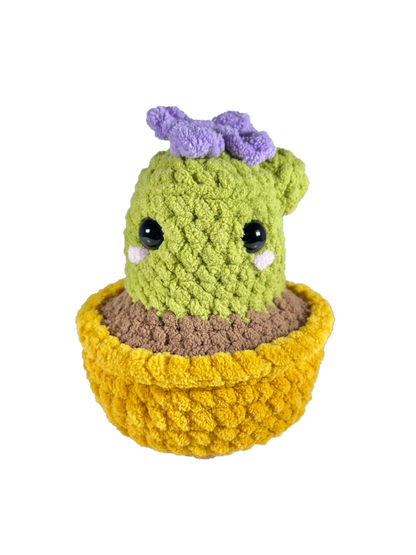 Crochet cactus plushie in a yellow pot plushie with a purple crochet flower on top.