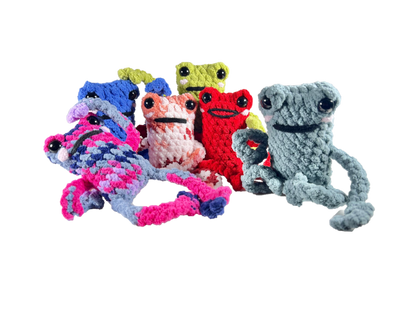 Family of crochet frogs in various colors all in funny poses looking ahead.