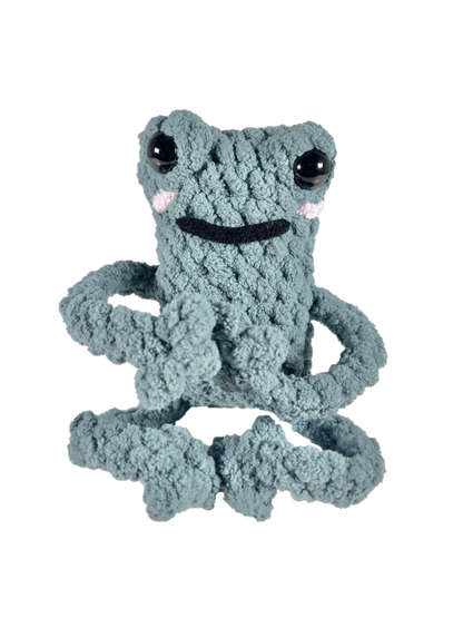 Green crochet frog in yoga pose.