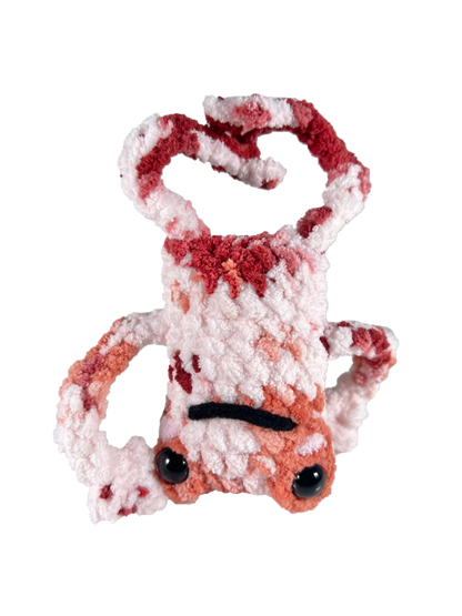 White crochet frog plushie with multiple colors mixed in such as orange and red, and doing a head spin pose.