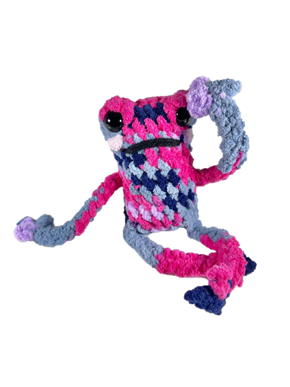 Dramatic multicolored crochet frog plushie in dramatic pose.