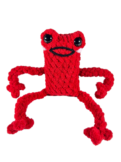 Red crochet frog plushie in excited pose smiling.