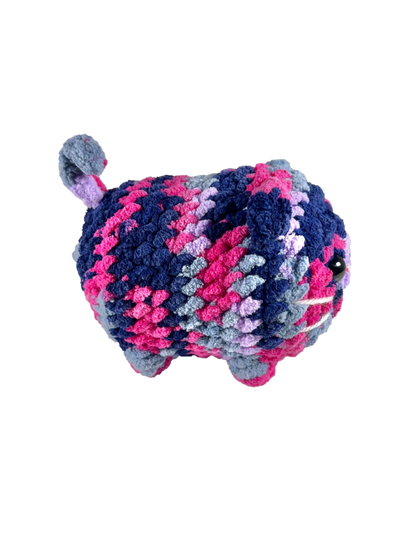 Multicolored crochet loaf cat plushie with a pink, and blue mix facing sideways.