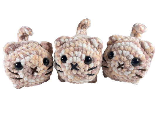 Three brown and white mixed color crochet loaf cat plushies.