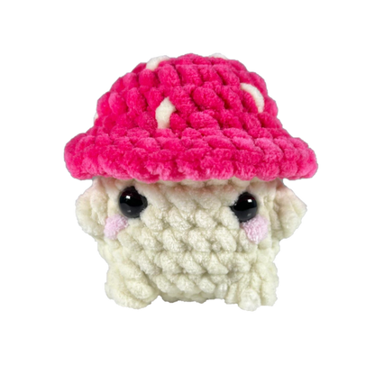 Pink crochet mushroom sitting looking forward.