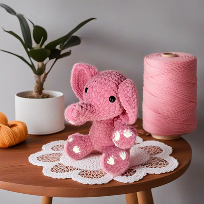 Pink crochet elephant sitting on top of table.