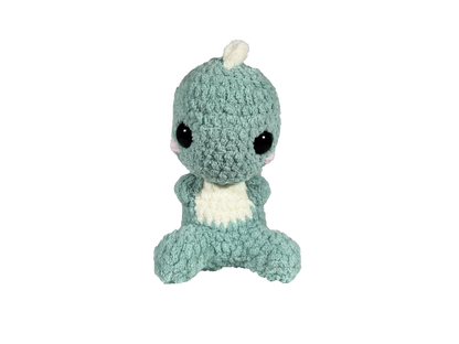 Green crochet dinosaur with soft spikes on its head and back looking forward.